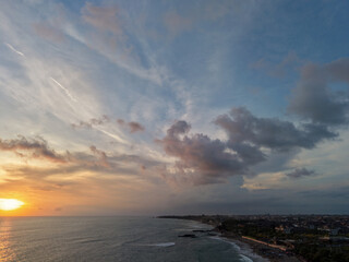 Obraz premium High angle aerial view of sunset over Batu Bolong coast in Bali with dramatic clouds and sea waves