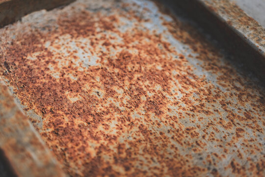 Close-up of rusted metal surfaces, including rusty nails and sheet metal in various tones of corrosion. Textured abstract industrial background with warm rusty colors.