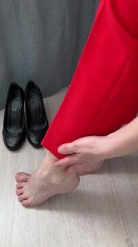 Vertical video. A woman rubs her tired legs. Relaxation, a feeling of release from discomfort and tension after wearing uncomfortable shoes