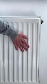 Vertical video. A woman checks the radiator. A woman's hand in a knitted sweater touches the heater. The theme of household worries, seasonal chores and attention to comfort in the house