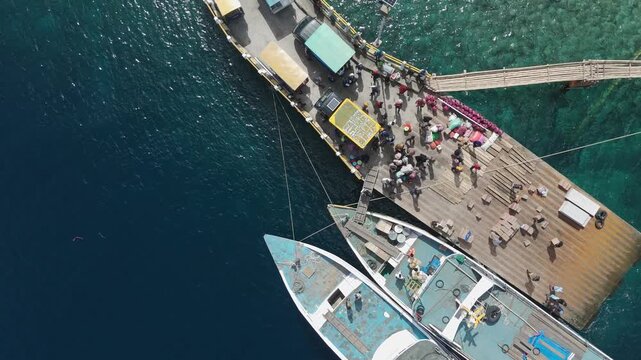 Aerial view of Portree town with colourful houses and fishing boats in Indonesia. Scenic view of the natural harbour and port by high ground and cliffs. Popular tourist destination on the Wakatobi Isl