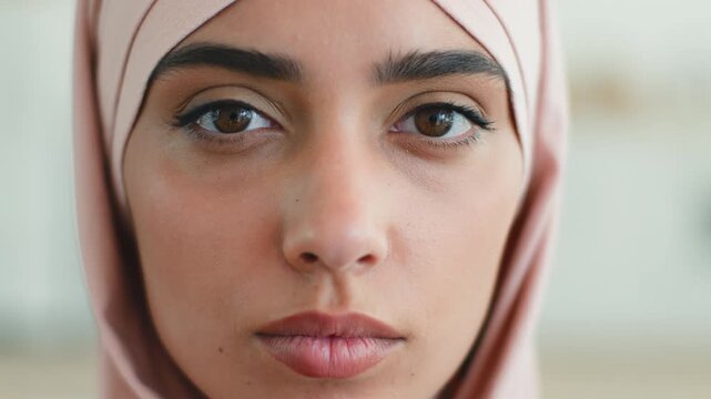 Close up portrait of serious calm Islamic woman at home indoors pensive Muslim girl Arabian lady in hijab thinking looking at camera ethnic female reflecting thoughtful healthy skin human diversity