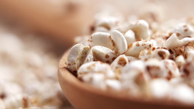 Organic puffed buckwheat cereal falling into a wooden spoon. Crispy gluten free grains. Healthy breakfast ingredient
