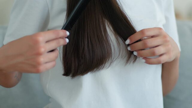 Cropped unrecognizable woman brushing dark hair combing at home indoor healthy female girl haircare routine using brush conditioner shampoo mask cosmetic smooth hairstyle hairstyling beauty treatment