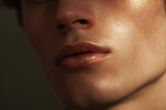 Male close crop of lips and philtrum with golden highlight and dewy skin for beauty layout and skincare background design