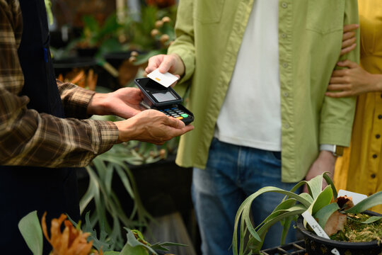 Cropped Shot of Customer Tapping Credit Card on POS Terminal at SME Plant Shop to Complete Purchase