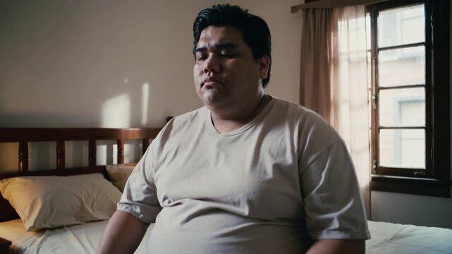 Noticing morning light man at home turning toward window sitting thinking in beige tee, gray sweats
