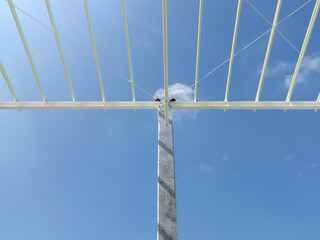 Fototapeta premium Modern steel roof structure supported by concrete columns stands prominently against clear blue sky, showcasing contemporary industrial architecture and engineering design.