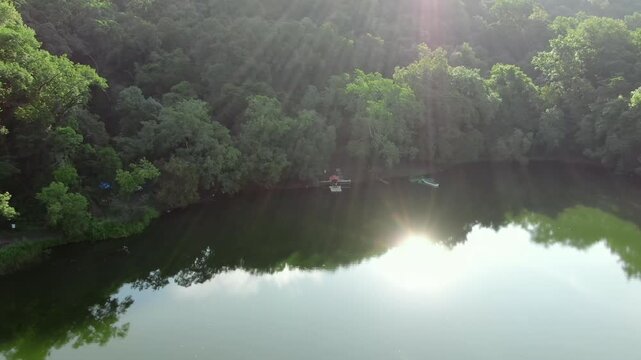 Calm waters of Laguna La Mar&iacute;a surrounded by dense tropical forest near the base of Volc&aacute;n de Colima in Colima, Mexico. Backward ascending aerial