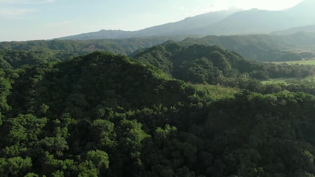 Drone flyover forest canopy covering rolling hills near Laguna La Mar&iacute;a at the base of Volc&aacute;n de Colima in Colima, Mexico.