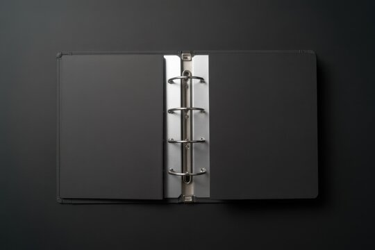 A sleek black binder lies open on a dark surface showcasing its silver rings.