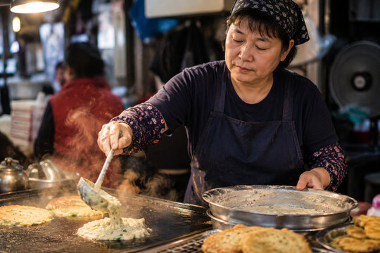 Korean market vendor cooking mung bean pancake at dawn