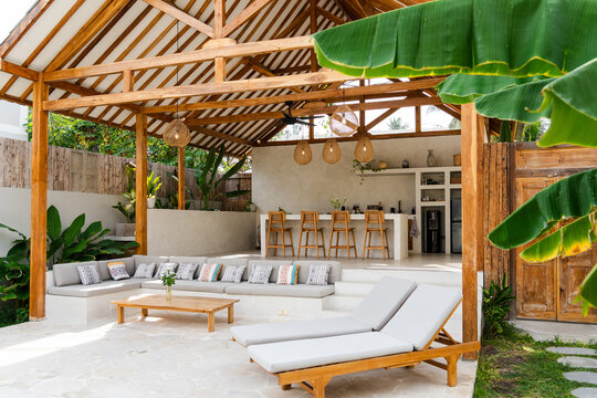 Luxurious outdoor living area featuring a wooden gazebo, lounge seating, and a modern bar