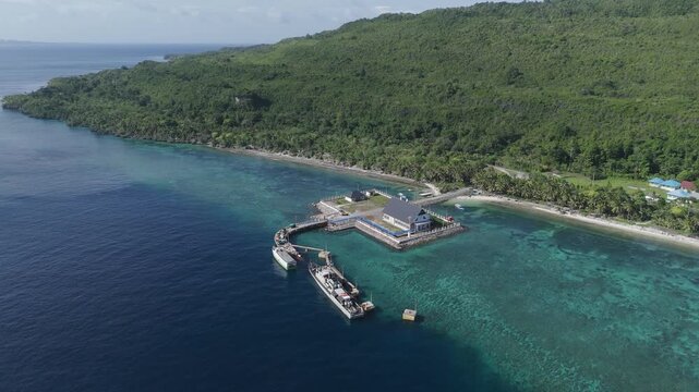 Aerial view of Portree town with colourful houses and fishing boats in Indonesia. Scenic view of the natural harbour and port by high ground and cliffs. Popular tourist destination on the Wakatobi Isl