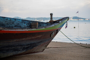 Traditional Thai longtail boat anchored on a quiet tropical beach with calm sea, distant islands and dramatic evening clouds. © Max