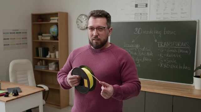 Portrait shot of middle aged male teacher with beard posing for camera with filament during school lecture in 3D modeling classroom