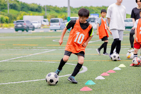 フットサル練習でドリブル指導を行う男性コーチと少年たち