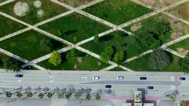 Aerial video over the coastal avenue of Vlora, Albania, featuring modern apartment rooftops, a palm lined boulevard with moving traffic