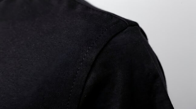 Close-up of a black shirts shoulder and upper back, showcasing fabric texture and design details.