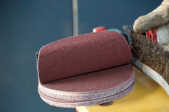Stack of abrasive sanding discs ready for use with a wire brush and glove
