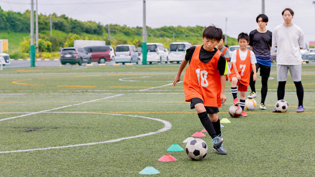 フットサル練習でドリブル指導を行う男性コーチと少年たち