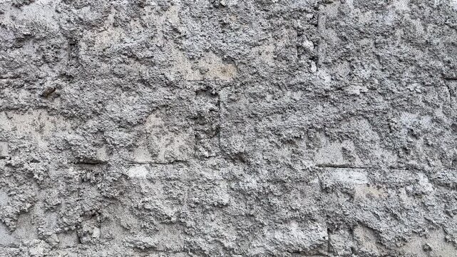 Rough cement plaster wall texture with coarse sand finish and unfinished construction surface in close-up view.