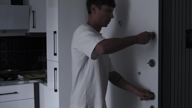 Agoraphobia and paranoia concept with frightened man quickly locking apartment door, fear, anxiety, unsafe world and psychological panic atmosphere