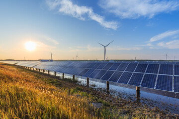 Naklejka na ściany i meble Coastal hybrid renewable energy farm with solar panels and wind turbines at dusk