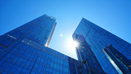 Low angle view of modern glass skyscrapers with bright sunburst in blue sky glass facade high rise © Fx Studio