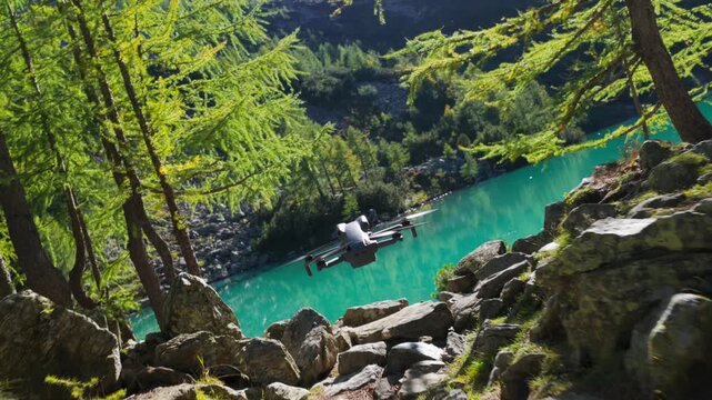 Close-up of DJI Mini series drone flying over turquoise water of alpine lake surrounded by larch forest