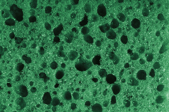 Macro, closeup of green foam sponge texture with porous, spongy and bubbly surface pattern suitable for abstract background design. Foamed polyurethane material surface