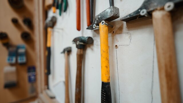 Hammers and other work tools neatly arranged on a workshop wall