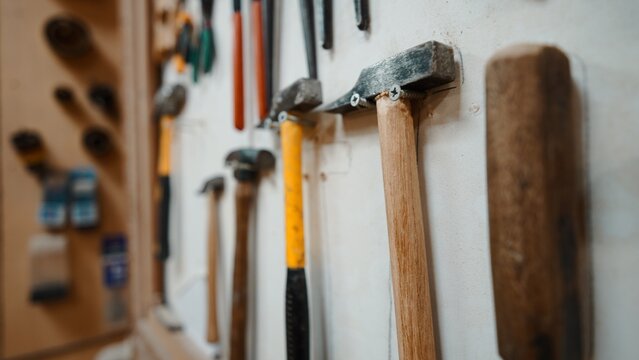 Workshop wall featuring various hammers and hand tools for artisan work