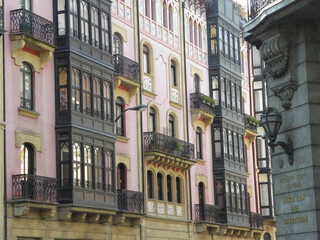 Belle Epoque Ensanche Facades Bilbao — Pink Brick Building with Azulejo Tile Friezes, Dark Wooden Galleries and Cream Stone Building, Bilbao, Basque Country, Spain © PicToMeOne