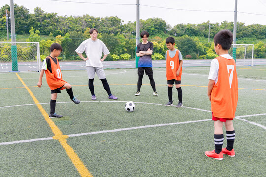 フットサル練習でパス練習をする少年チームと男性コーチ