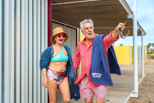 Senior couple enjoying summer vacation at beach changing cabin
