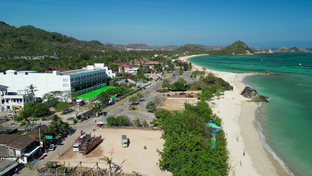 Stunning overhead panorama of Kuta Lombok coastline featuring tropical shoreline palm trees and crystal clear sea under blue sky
