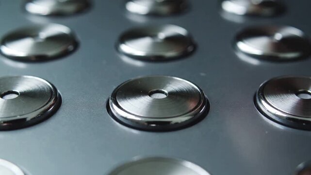 Contacting fingertip depressing circular button on metal panel, activating device function