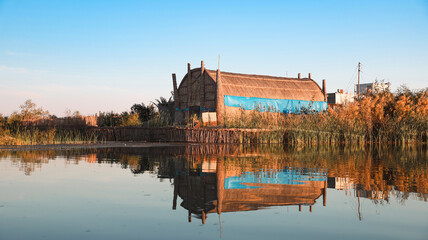 Fototapeta premium Traditional house reflected in water at Mesopotamian Marshes in Iraq during calm morning