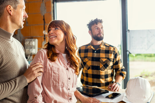Portrait of adult couple with a contractor at a house construction site.