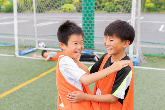 サッカーでゴールを決め笑顔で抱き合う少年たち