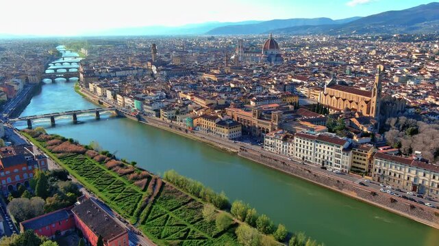 4K aerial view of Florence with Brunelleschi's Duomo dome, Giotto's Campanile, Palazzo Vecchio, Santa Croce, Ponte Vecchio and the Arno River flowing through Tuscany.