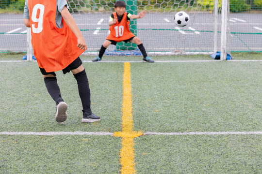 サッカーでシュートをする少年選手とゴールキーパー