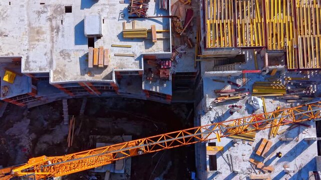Bird's eye view capturing yellow wooden beams and steel reinforcements on a residential project site. Overhead shot of tower crane boom over construction formwork