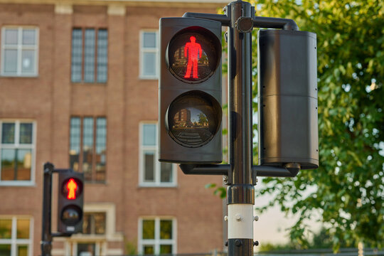 Red Pedestrian Signal Stands Tall Amidst the Vibrant City Center of Amsterdam, Guiding Footsteps Safely Across the Bustling Streets