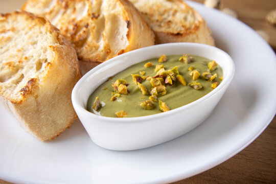 Pistachio dip with toasted bread slices on a white plate