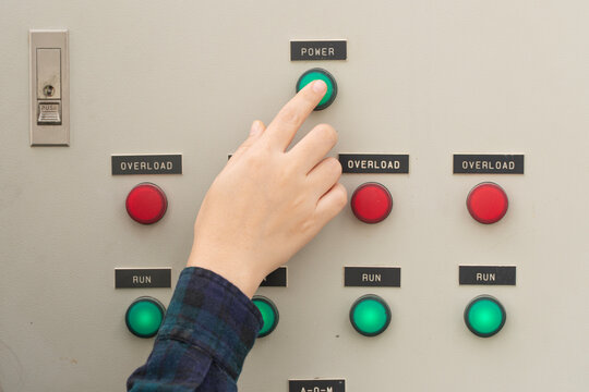 Close up of a farmer's hand pressing a green power button on an electrical control panel. Perfect for smart agriculture, automation systems, and industrial technology concepts.