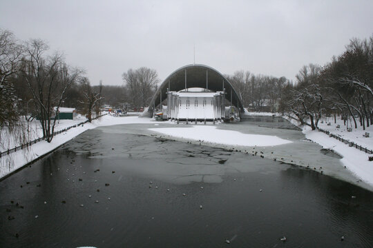 Summer Theater Shell in Lazar Globa Park, Dnipro, Ukraine, January 2009. Frozen lake with thin ice, snow, and swimming ducks in front of the iconic modernist architectural building
