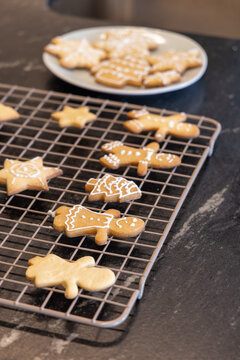 Decorated gingerbread cookies cooling on metal rack on dark stone counter with white icing details