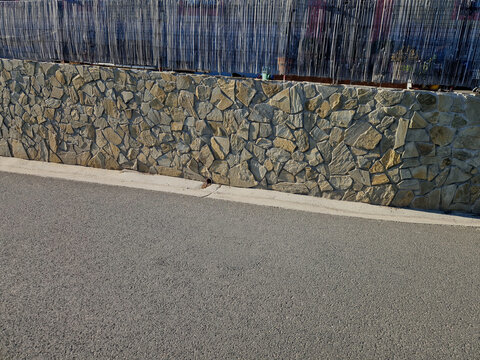 retaining wall with facing stone cladding made of irregular chipped often referred cyclopean masonry or wild stone. stabilization of slopes, leveling terrain irregularities or as decorative fencing. B
